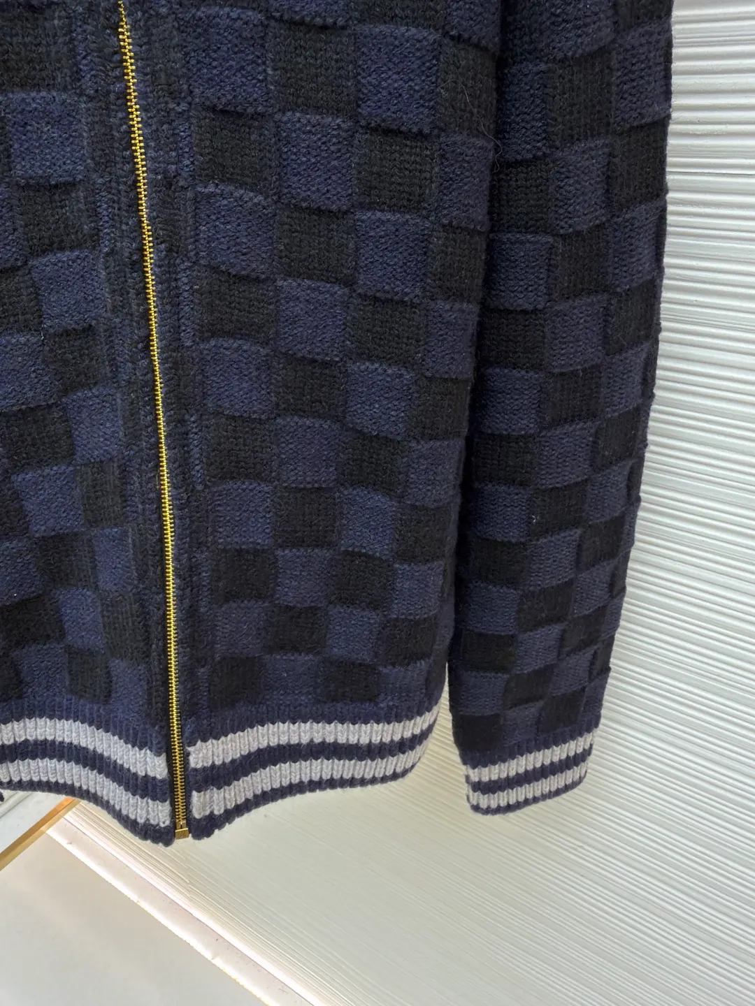 LOUIS VUITTON knitted waist contrast ribbed collar sweater ●Original version: Purchased and developed by 20433 ●Item number: 1682136-C15 ●Fabric: wool blended fabric ●Technology: knitted ●Color: black and blue ●Version: fitted version ●Weight: about 1360 grams ●Size: S-M-L-XL ●Description: This Louis Vuitton checkerboard knitted zipper jacket is made of double-ply merino wool blended yarn and is woven with a 12-needle three-dimensional knitting process on a German Stoll computerized flat knitting machine. The Damier checkerboard pattern on the body uses intarsia knitting techniques, and the layered interweaving of dark blue and black yarns creates a 3D concave and convex texture. There is no printed patchwork process, and the pattern and the body are integrated for a more textured look. The neckline is designed with contrasting ribbed lapels, and built-in spandex elastic yarn improves resilience; the metal zipper is made of gold-plated brass, and the teeth are precision polished. The zipper track and the seam of the body are sewn with overlock stitching, and the stitch length is controlled within 0.2cm. The contrasting ribbed edges on the cuffs and hem are pre-shrunk and hand-shaped and ironed, making the garment crisp and less likely to loosen after long-wearing. Every detail demonstrates the brand's strict standards of high-end knitting technology. The overall wiring is straight and delicate, the fabric is comfortable and soft, and the color is consistent without color difference. It can be matched with the same style to create a fashionable look and control various occasions. Customized accessories, complete with three standards, same style for men and women!